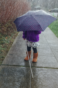 young girl holding a cane and umbrella walking in the rain young girl holding a cane and umbrella walking in the rain